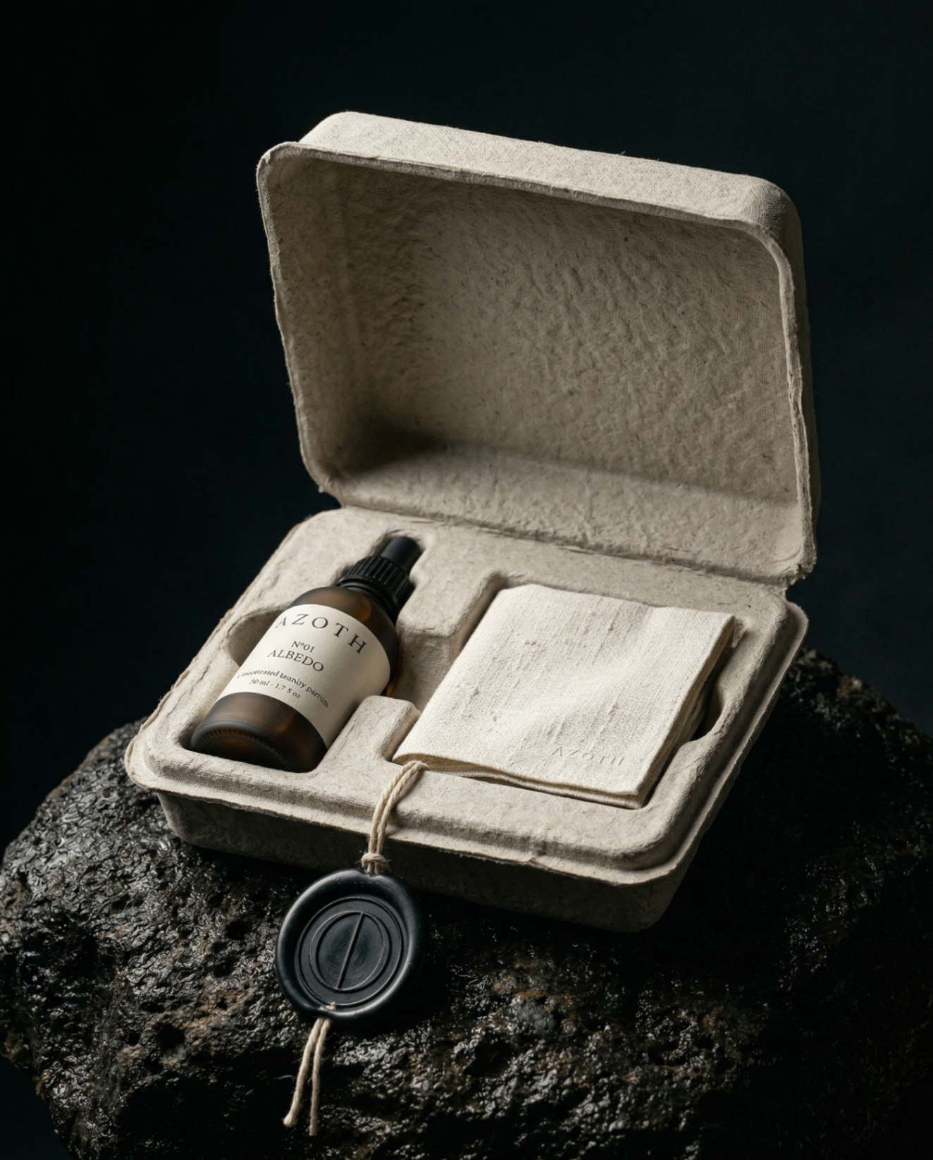 The amber dropper bottle and a folded raw linen cloth, photographed from above on warm grey concrete.